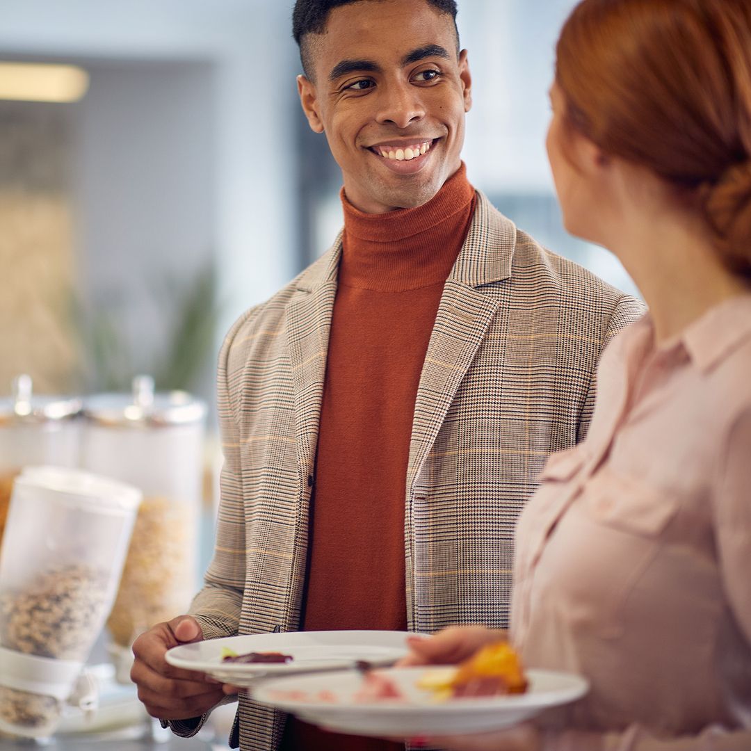 Ein Herr der sich mit einer Dame beim Frühstücksbuffet unterhält.